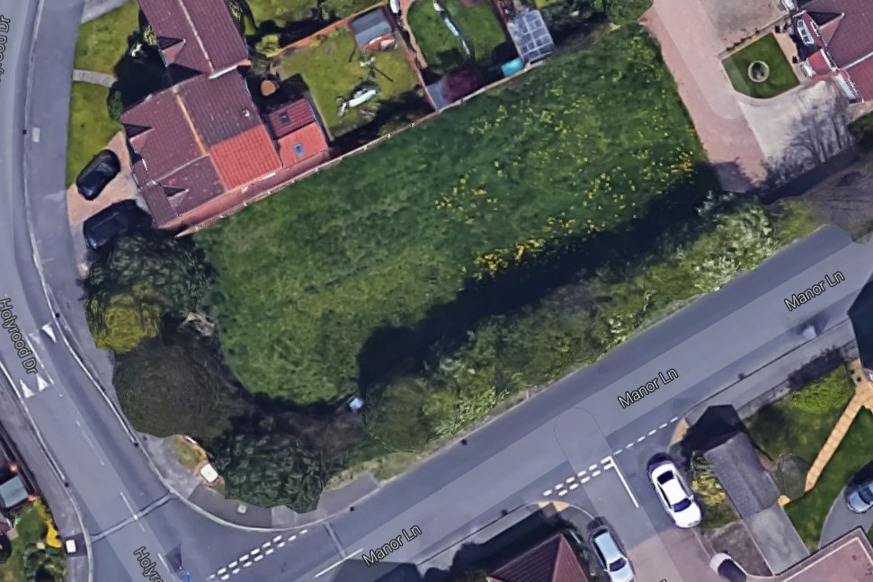 Aerial view of the former vacant paddock at the junction of Manor Lane and Holyrood Drive, Rawcliffe, York, showing overgrown vegetation and mature hawthorn hedge boundary prior to residential development