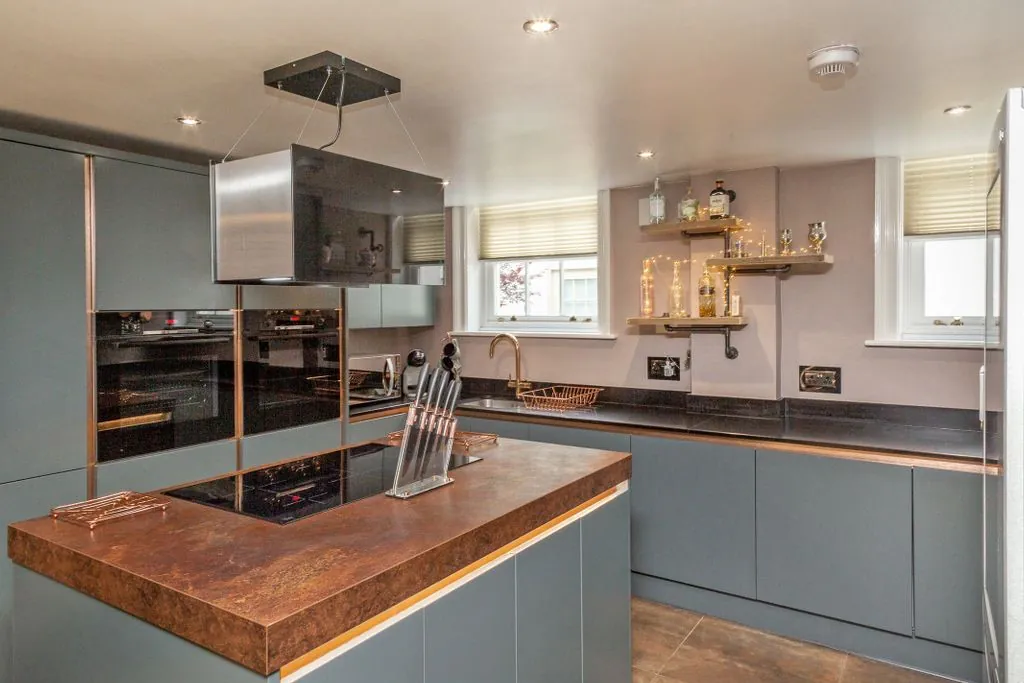 A minimalist white kitchen with a wooden dining table, part of a sympathetic conversion of listed buildings in York.
