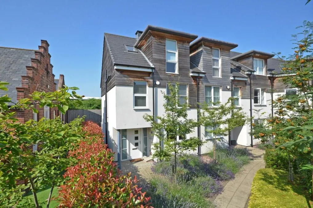 Contemporary extension to a listed building in York, featuring modern balconies and dark cladding adjacent to the historic Victorian school brickwork.