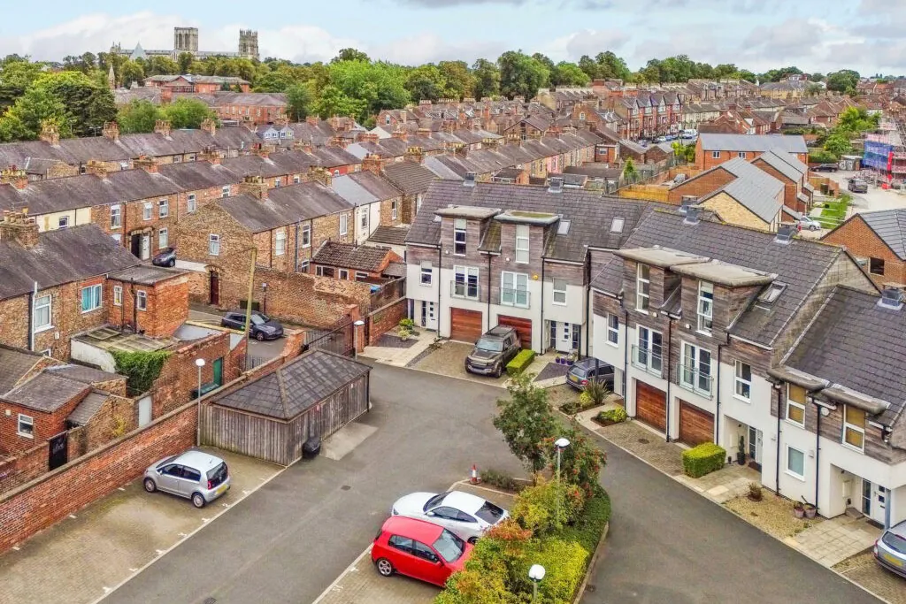 Contemporary townhouses with dark grey cladding and modern windows, part of a brownfield residential development in York near the listed school.
