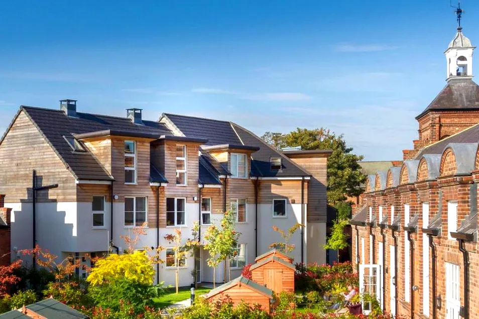 Contemporary townhouses adjacent listed building showcasing modern cedar cladding that will silver over time and large windows and Zinc cladding at the Bootham Green residential brownfield development in York.