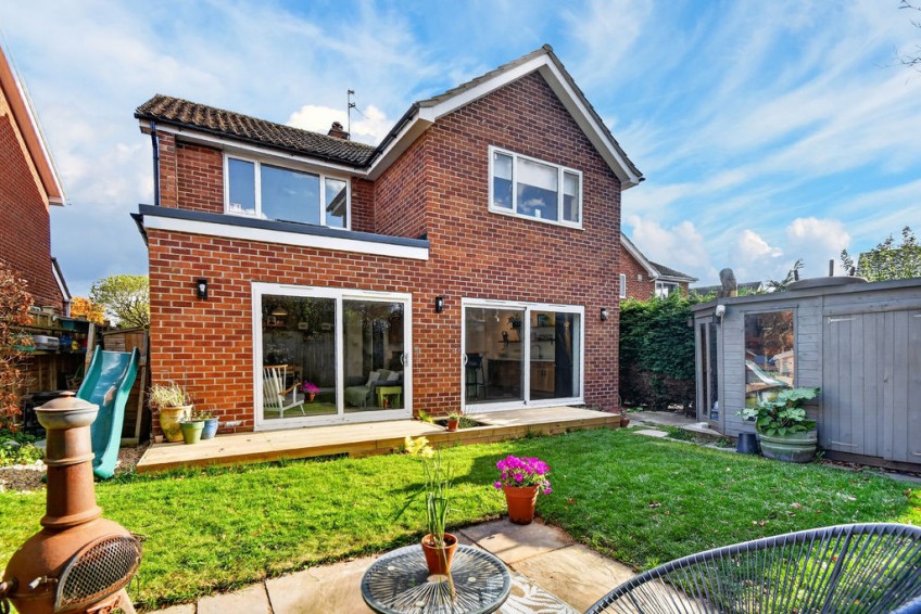Red brick exterior of a completed two storey front and rear extension in Nether Poppleton, York, featuring a single-storey flat roof element, sliding glass doors, and a newly laid garden deck.