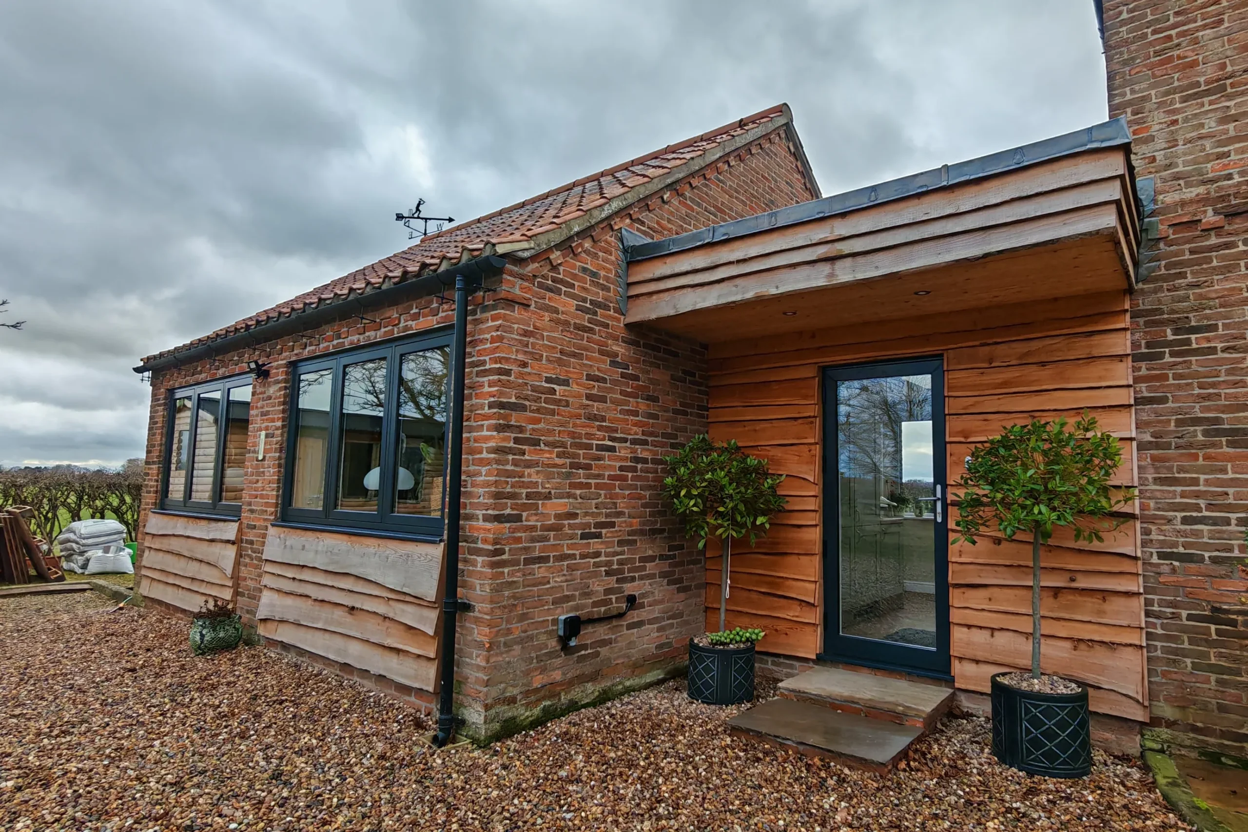Flat roof link extension with lead coverning and detailed flashing, timber cladding and brick lower course, in Nether Poppleton, York, North Yorkshire