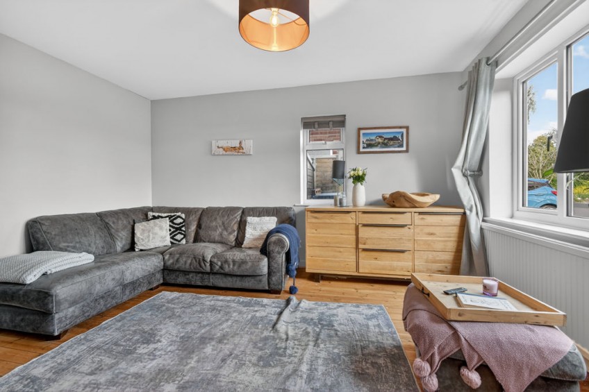 Cosy living room featuring a grey corner sofa, a modern log burner, and a blue feature wall, successfully renovated alongside a whole-house two storey front and rear extension.