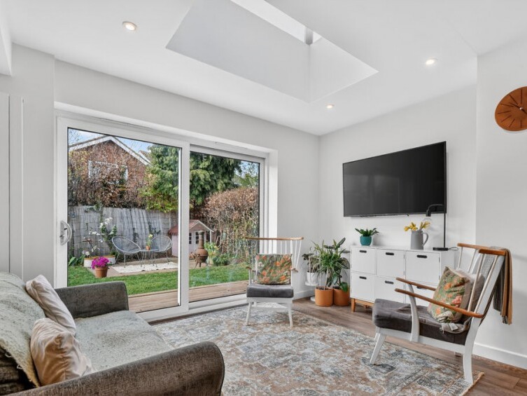 Relaxing seating area positioned under a modern skylight with large sliding glass doors opening directly to the garden, forming part of a comprehensive two storey front and rear extension.