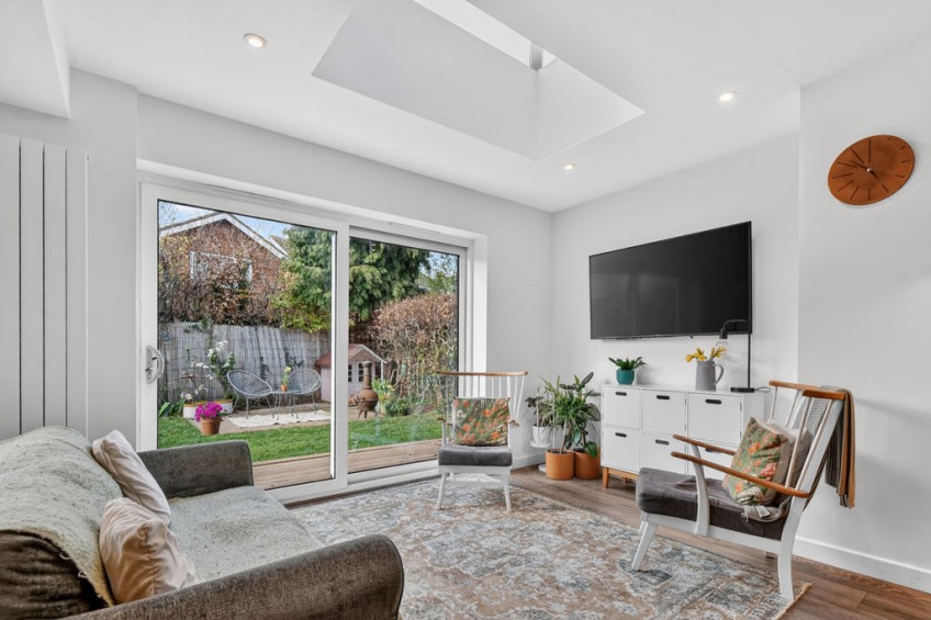 Relaxing seating area positioned under a modern skylight with large sliding glass doors opening directly to the garden, forming part of a comprehensive two storey front and rear extension.