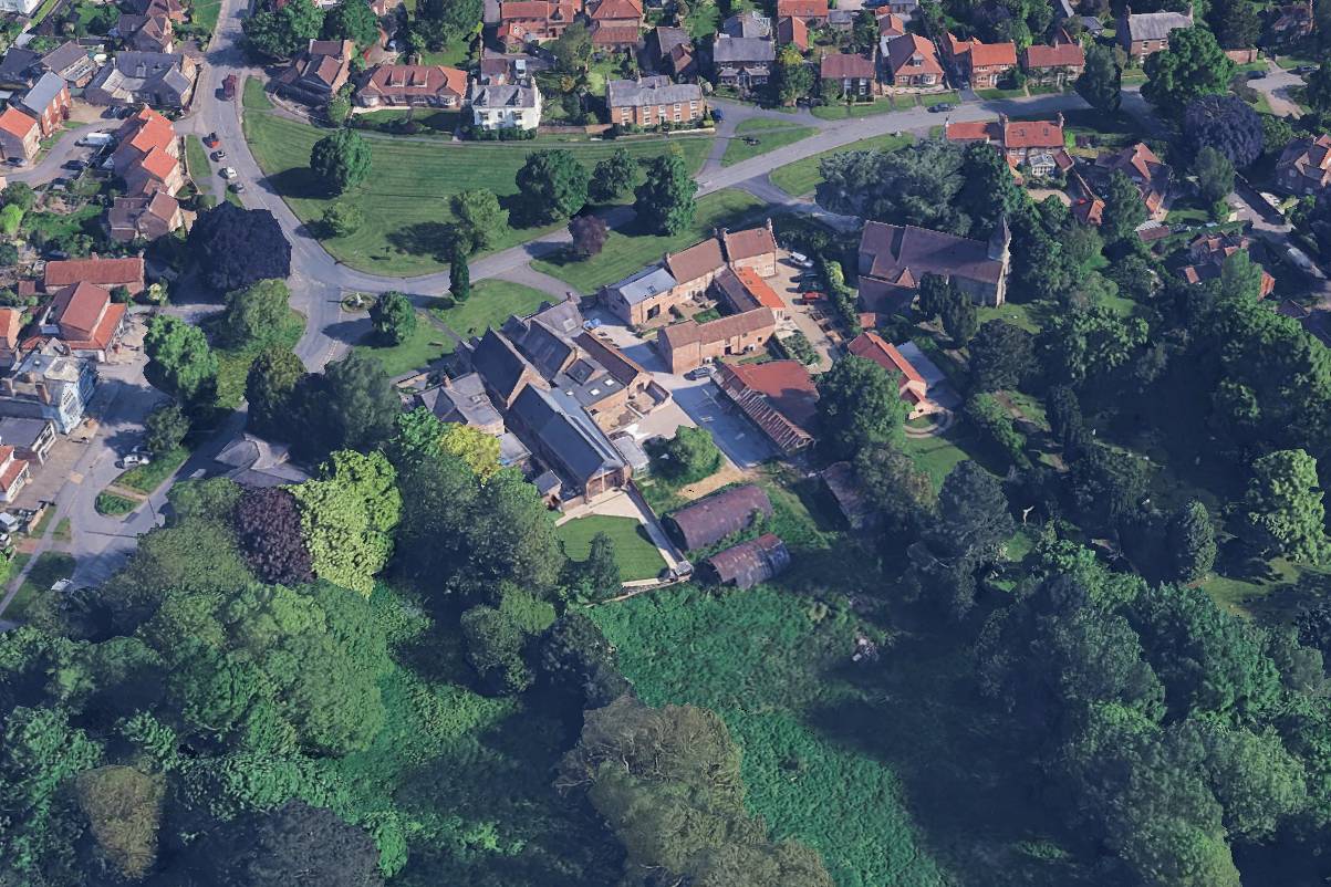 Aerial view of Model Farm, Upper Poppleton, York, showing the Grade II listed farmstead complex, village green, All Saints Church and surrounding Conservation Area