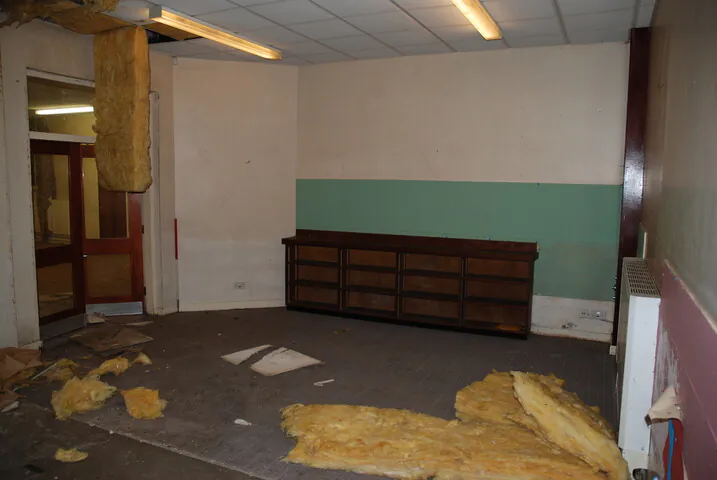 A corner of an empty classroom with debris and old cabinetry, illustrating the brownfield state of the Grade II listed building before the Fining Associates redevelopment.