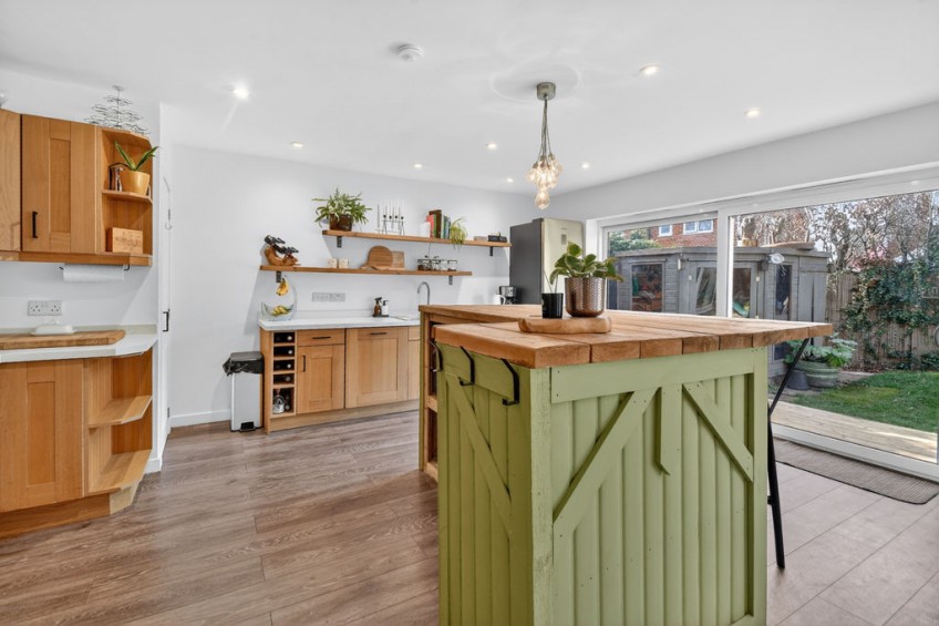 Open-plan kitchen diner with natural wood countertops and large sliding glass doors leading to the rear garden, achieved through a comprehensive two storey rear extension.