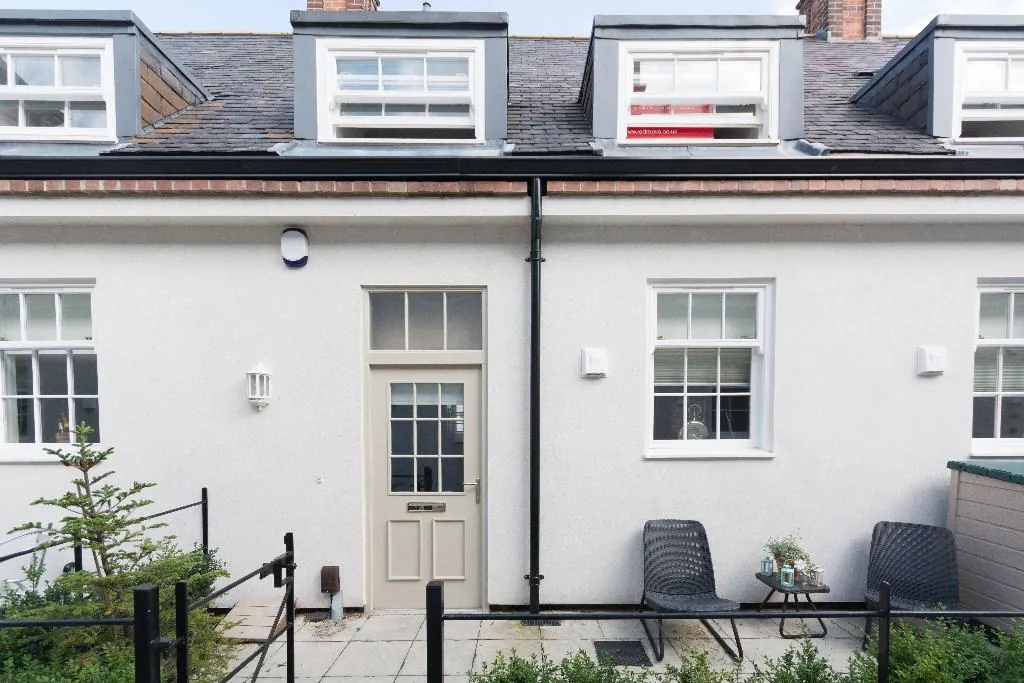 A row of cream-rendered residential units with black doors and dormer windows, part of a listed building conversion York at Bootham Green.