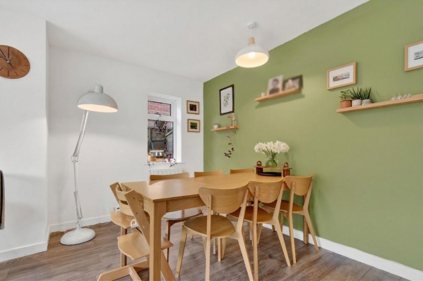 Wooden family dining table set against a green feature wall within the new open-plan space of a two storey front and rear extension in Nether Poppleton.