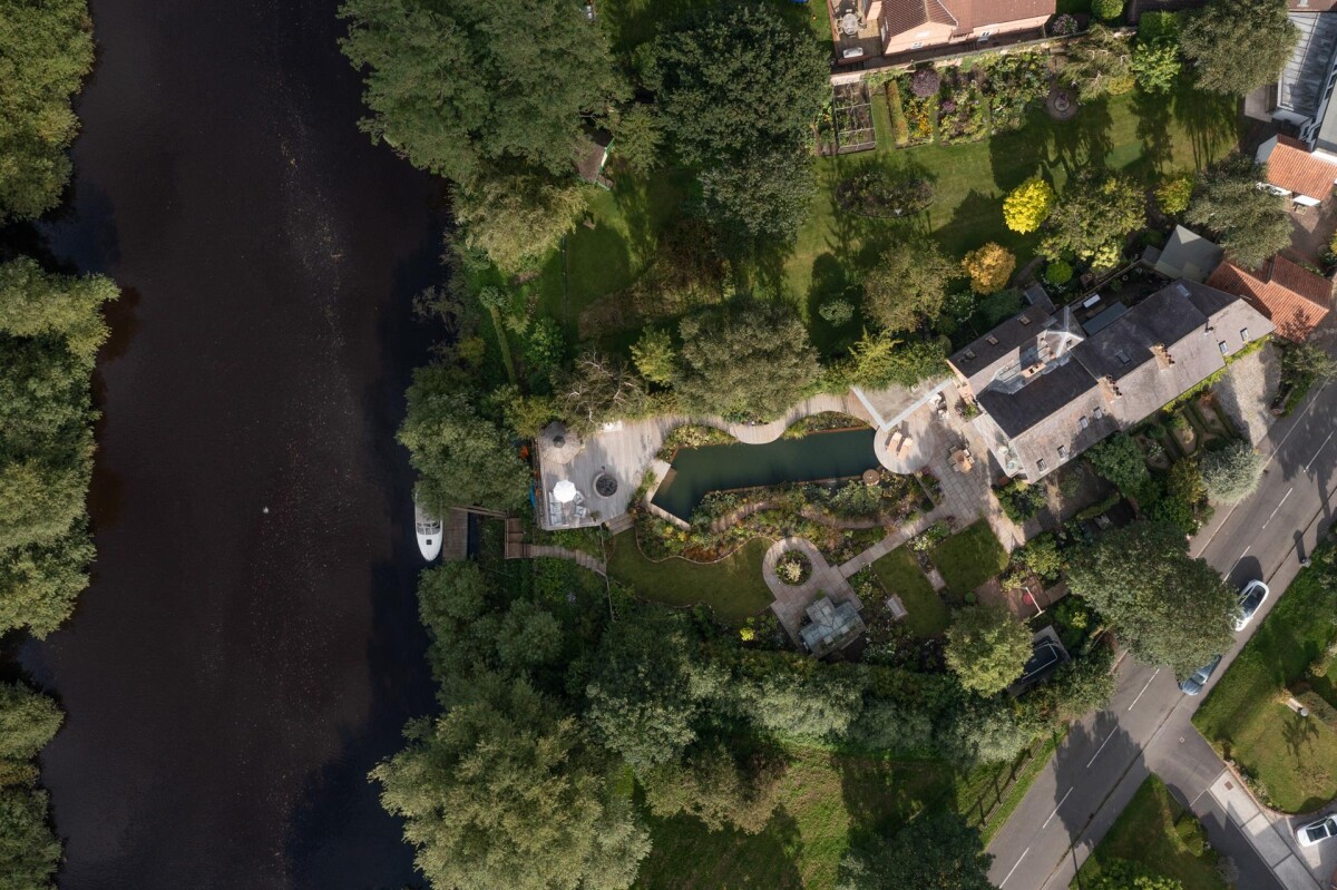 Aerial view showing River Ouse, full plot and double storey extension in Nether Poppleton conservation area York, with natural pool and riverside garden