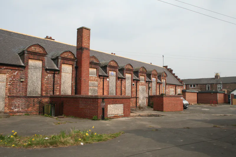 A long view of the Shipton Street School facade in York showing a row of boarded-up, tall arched classroom windows typical of Victorian school architecture.