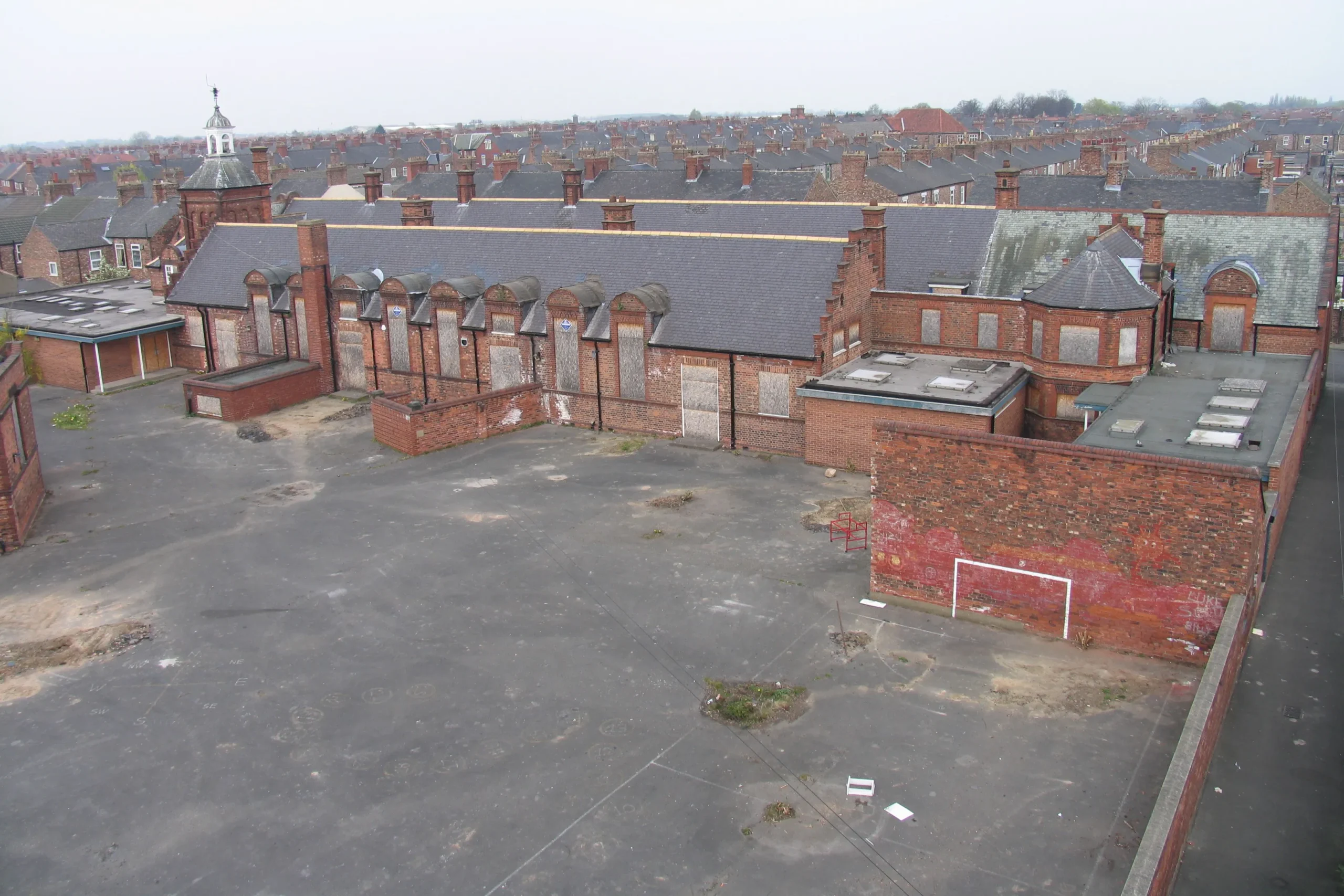High-angle view of the derelict Shipton Street School buildings and large tarmac playground in York, showing the site before its residential redevelopment.