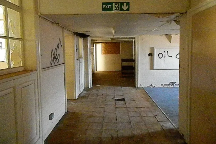A derelict interior corridor within the former Shipton Street School in York, featuring broken flooring and graffiti before its brownfield residential development.