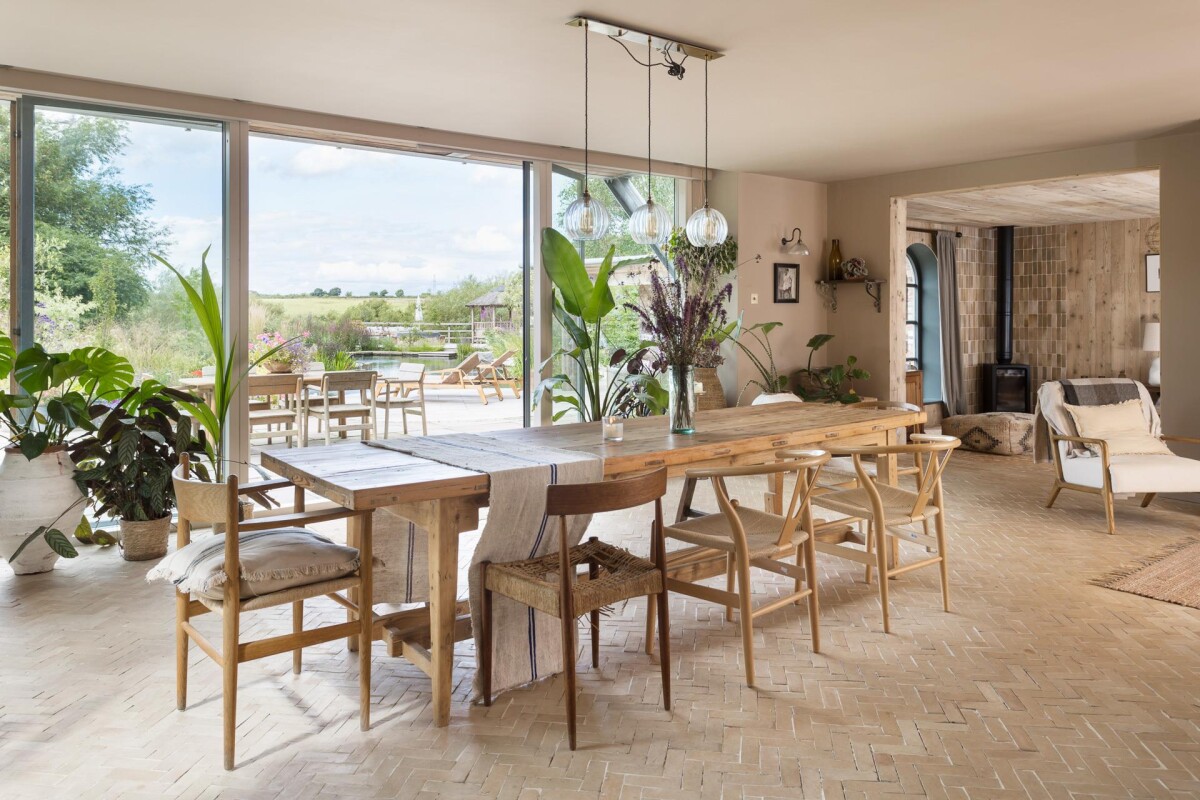 Dining room in period property extension in York with floor-to-ceiling glazed wall framing open countryside and natural pool views, Nether Poppleton conservation area