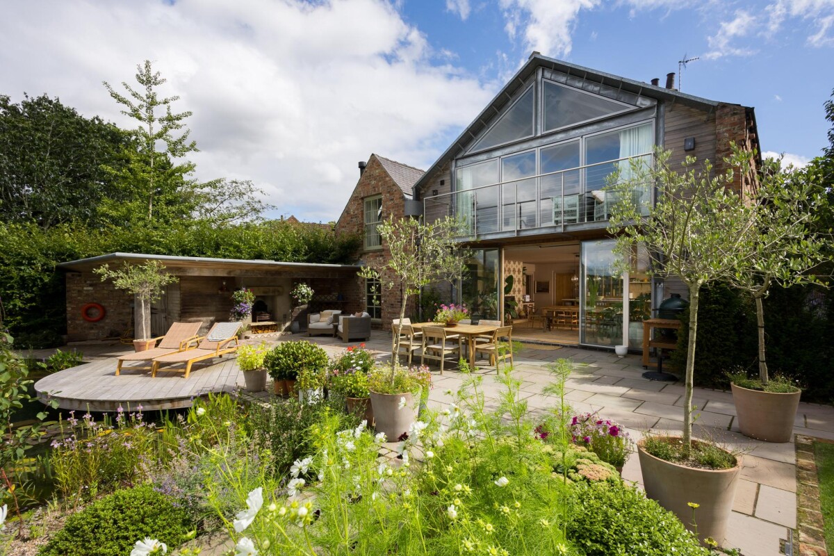 Rear terrace of double storey extension in Nether Poppleton conservation area York, with glazed gable, balcony, outdoor dining and landscaped garden