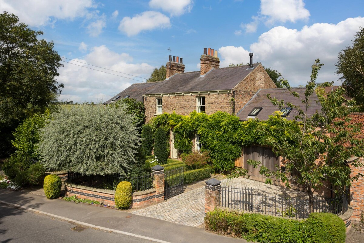 Front elevation of Georgian cottage on Main Street, Nether Poppleton conservation area York, showing original brick facade, sash windows and wrought iron railings