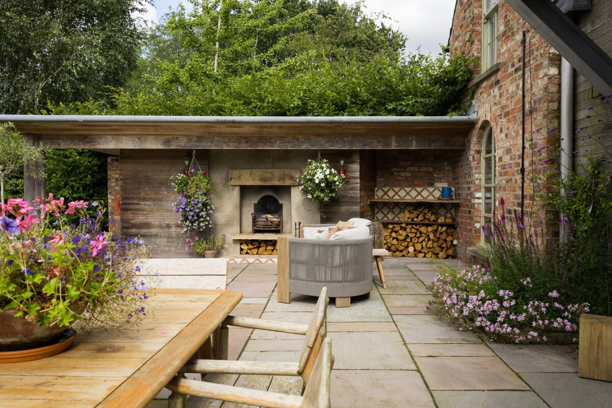 Outdoor loggia with open fireplace and York stone terrace adjacent to period property extension, Nether Poppleton York