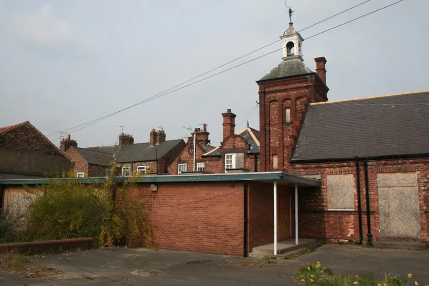 View of the original brick bell tower and boarded-up classroom windows at the Shipton Street School site in York before restoration by Fining Associates.