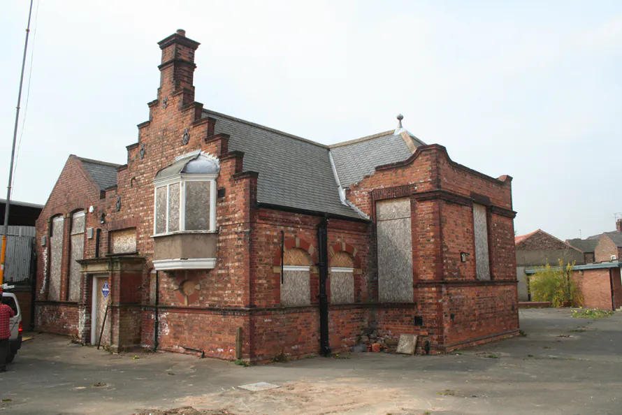 Exterior view of the weathered red brick gables and boarded windows of the Shipton Street School in York, a key site for sympathetic conversion of listed buildings.