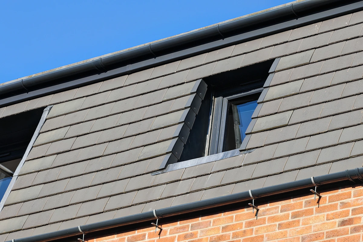 Architectural detail of an angled dormer rooflight recessed flush within the dark grey slate mansard roof of Hawthorn Street Apartments, Layerthorpe York — precision contemporary detailing referencing the site's industrial heritage.