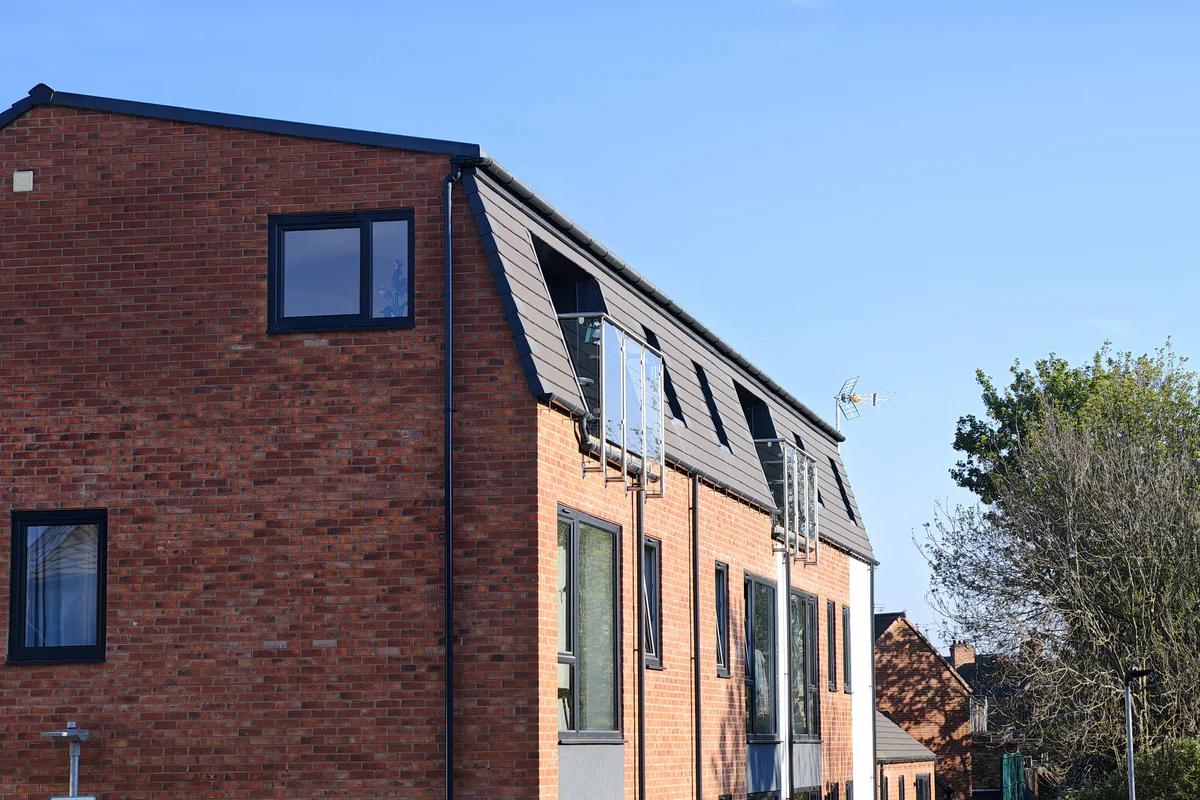 Corner elevation of Hawthorn Street Apartments, Layerthorpe York, showing the junction of the north gable and west cycleway elevation with dark slate mansard roof and recessed dormers — an urban infill residential scheme designed by Fining Associates chartered architects York.