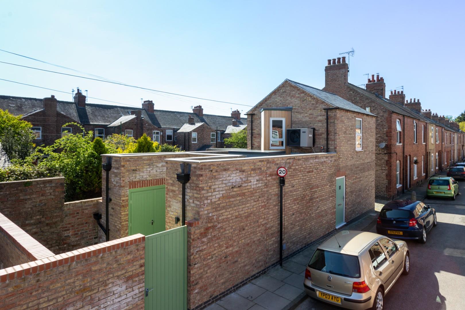 The completed new build residential property at 175 Burton Stone Lane, designed by Fining Associates. The image shows a modern part-two-storey home featuring context-appropriate brickwork, a steep pitched roof, and the strategic angled first-floor window accented with timber cladding to protect neighbour privacy.